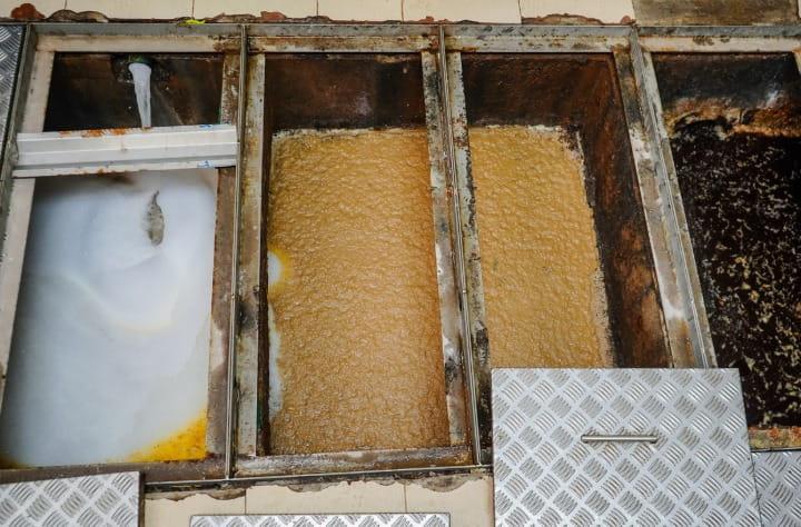a worker removing grease from a commercial kitchen grease trap